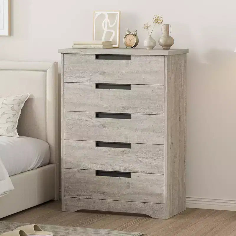 Commode cinq tiroirs avec poignées intégrées, meuble de rangement moderne en bois, compact et peu encombrant, adapté aux salons.